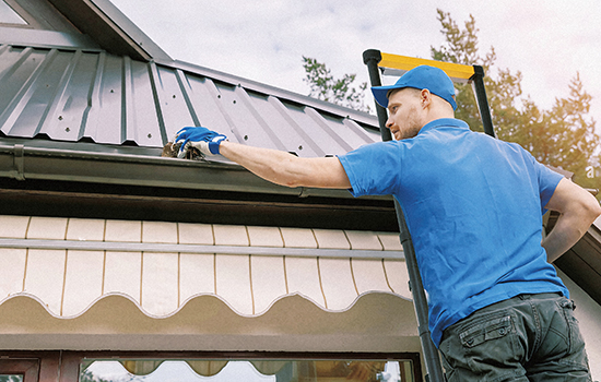 Handwerker repariert das Dach des Hauses mit aluleiter ausziehbar